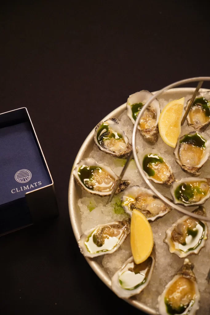 Fuente de ostras (ostiones) frescas de La Docena con limón y servilletas Climats