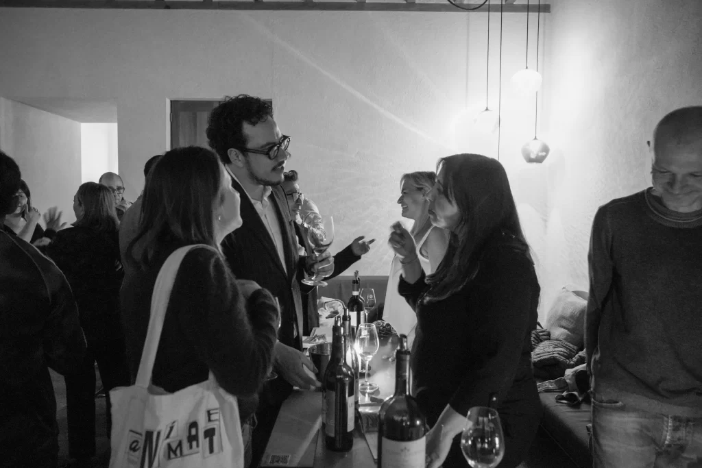 Los clientes están interactuando con Letizia, productora de vino italiano de la bodega Passopisciaro. Están catando los vinos y recibiendo explicaciones de los detalles técnicos.